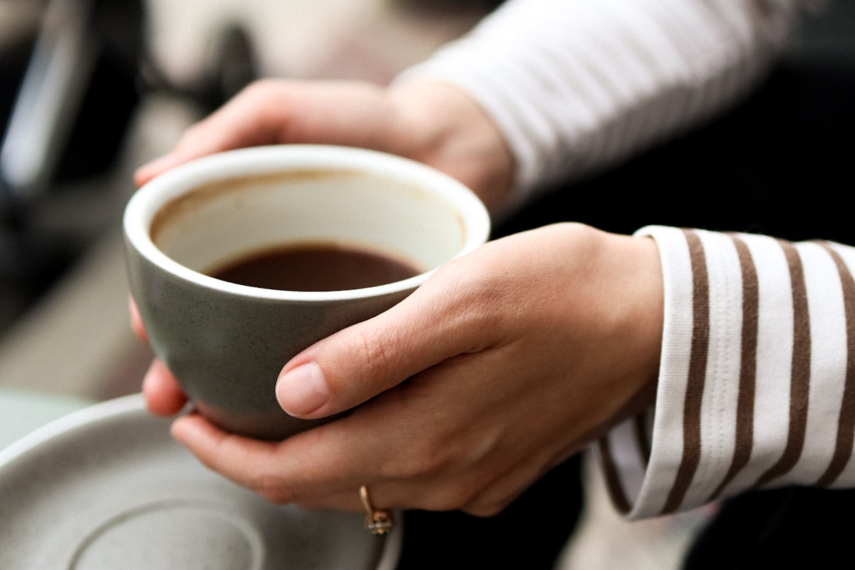 Hands holding a warm cup of coffee in soft light